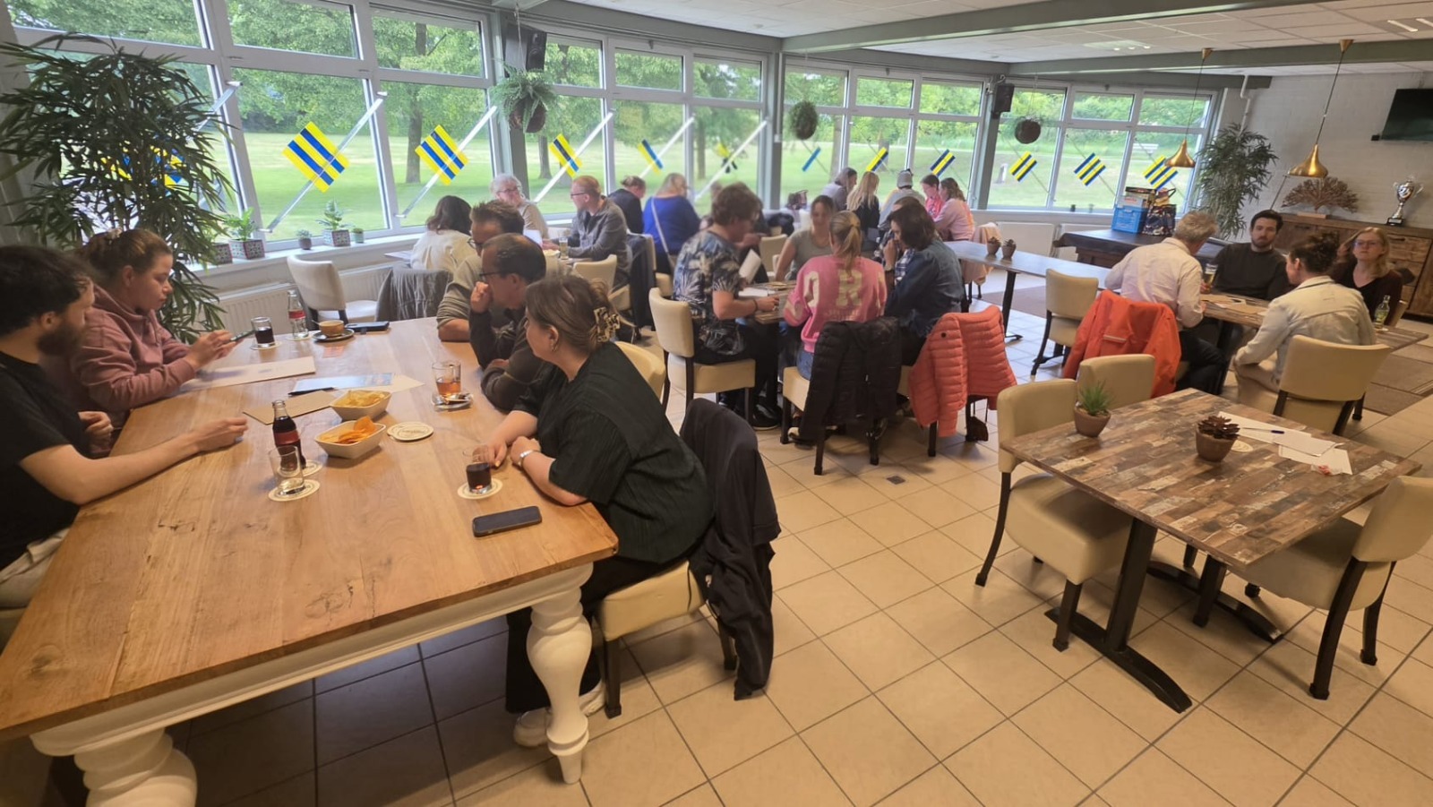 Groep deelnemers aan tafels tijdens een activiteit van Let's Meet Wijchen